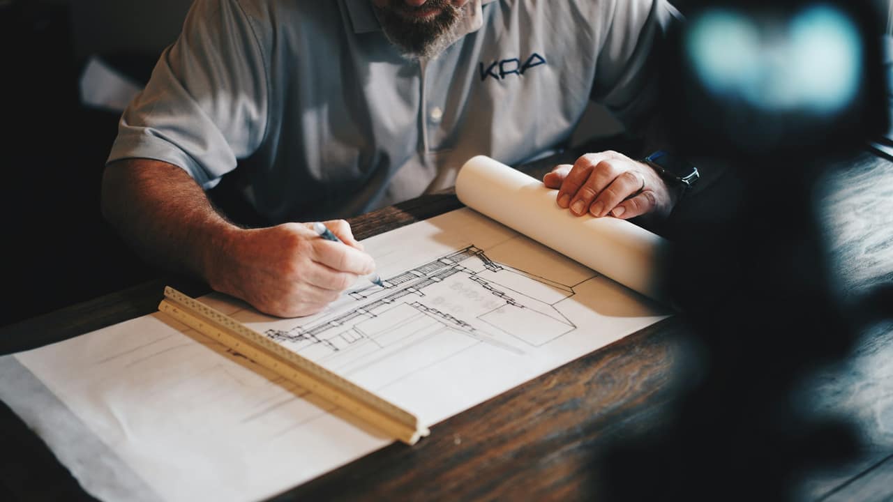 Maître d'oeuvre annotant des plans de construction avant un chantier en Moselle